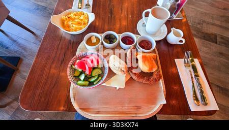 . La colazione a buffet include frutta fresca, pasticcini e caffè serviti su un tavolo di legno, creando un'atmosfera calda e invitante Foto Stock