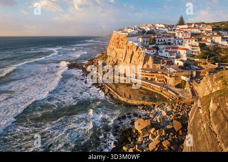 L'affascinante Azenhas do Mar, un pittoresco villaggio di pescatori arroccato sulle scogliere. Il sole tramonta sull'Atlantico, gettando calde sfumature sull'edificio imbiancato Foto Stock