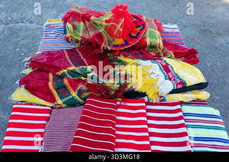 Una vivace mostra di tessuti tradizionali marocchini. Sono impilate, presentano righe audaci e strati di tessuti riccamente colorati con nappine e ven Foto Stock