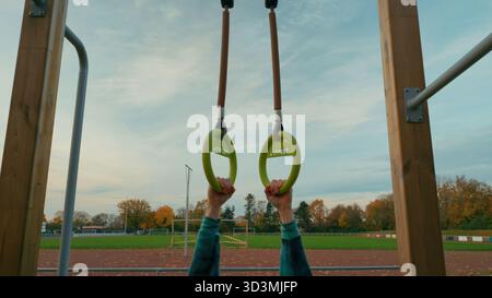 Mani che tengono anelli da ginnastica all'aperto, esercizio fitness e concetto di forza, stile di vita attivo e motivazione all'allenamento Foto Stock
