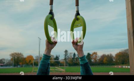 Mani che tengono anelli da ginnastica allenamento all'aperto, esercizio fitness e concetto di allenamento di forza, stile di vita sano e motivazione al parco sportivo Foto Stock