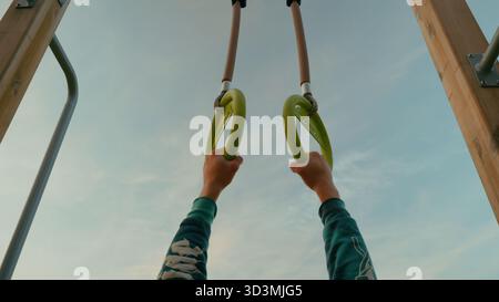 Mani che tengono anelli da ginnastica all'aperto, esercizio fitness e concetto di forza, stile di vita attivo e motivazione all'allenamento Foto Stock