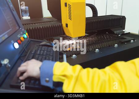 Taglio laser e operatore al pannello di controllo, CNC moderna tecnologia industriale Foto Stock