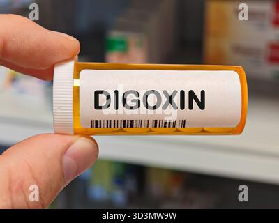 Scatola di plastica arancione di compresse di DIGOSSINA su un tavolo della farmacia dell'ospedale usato per trattare l'insufficienza cardiaca e le aritmie un glicoside cardiaco. Magazzino DELLA FARMACIA Foto Stock
