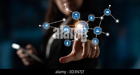 Una donna d'affari si avvale di un'interfaccia digitale futuristica con icone che rappresentano la tecnologia e la comunicazione in un ambiente professionale Foto Stock