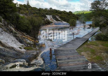 Il parco geotermico Orakei Korako presenta una passerella in legno su fumanti sorgenti termali, colorate terrazze minerali e una lussureggiante vegetazione circostante Foto Stock