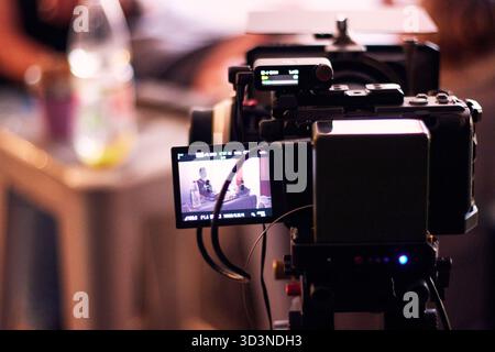 Dietro le quinte di una produzione audiovisiva, registrando film e monitorandoli attraverso schermi e telecamere. Del direttore e del team di produzione Foto Stock