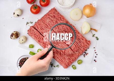 Lente d'ingrandimento con abbreviazione di ANALISI DEI RISCHI E PUNTI CRITICI e carne macinata cruda su sfondo chiaro Foto Stock