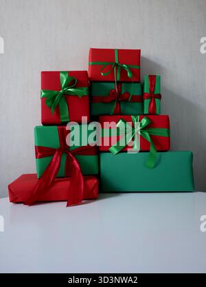 Set di regali collocati nella piramide. Scatole di diverse dimensioni, rettangolari e quadrate. Colori rosso e verde. Legato con nastri con archi opposti Foto Stock
