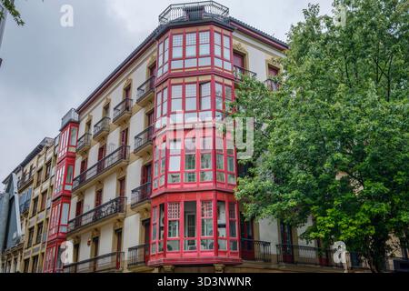 Edificio tradizionale ad angolo con finestre e balconi della Baia Rossa, facciata residenziale, architettura tipica di San Sebastián, Paesi Baschi, Spagna Foto Stock