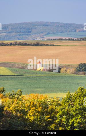 Pittoresco paesaggio caratterizzato da colline ondulate, campi e un affascinante edificio isolato con un distinto tetto rosso. Tranquillo paesaggio di campagna. Moravia reg Foto Stock