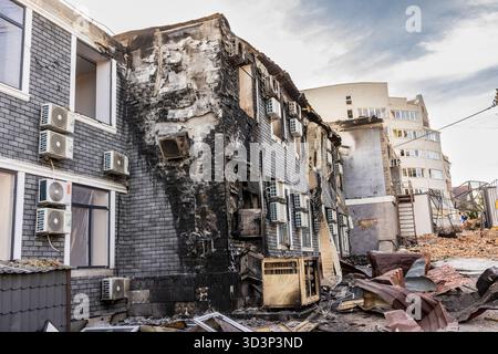 Vista aerea di edifici parzialmente intatti di distruzione urbana con unità AC a contrasto struttura danneggiata da incendio crollata e moderna torre di detriti sparsi Foto Stock