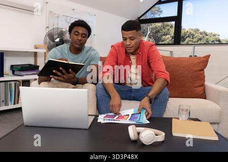 Revisione di esempi di progettazione, diversi colleghi maschi che collaborano al progetto in ufficio, con un notebook Foto Stock