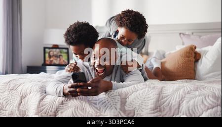 Bambini, Risate e papà con lo smartphone, la camera da letto e guardare i cartoni animati con un abbonamento o giocando. Bambini, uomo felice e nero con cellulare per film Foto Stock