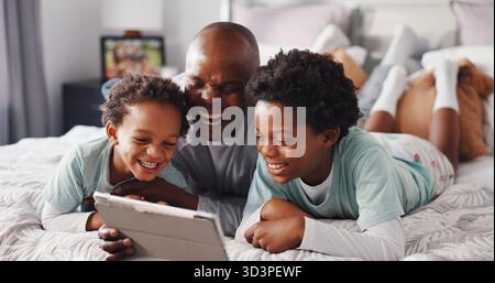 Bambini, Risate e papà con un tablet in camera da letto, legando e guardando i cartoni animati con l'abbonamento app. Uomo nero felice e rilassati con i bambini a letto Foto Stock