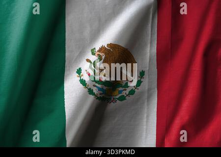 Bandiera messicana con strisce verticali verdi, bianche e rosse, con lo stemma nazionale e un'aquila che tiene un serpente nel becco e nel talone Foto Stock