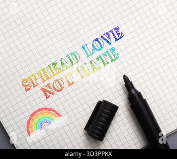 La frase Spread Love Not Hate è scritta a mano con un pennarello nero su carta, accompagnato da un arcobaleno colorato e da una penna, che rappresenta un messaggio di comp Foto Stock