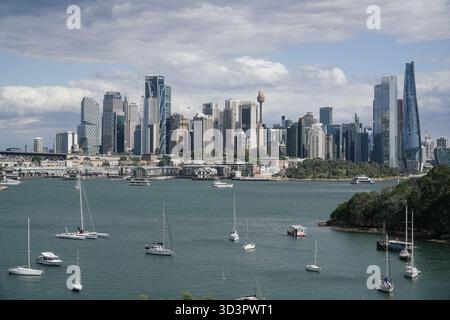 Lo skyline di Sydney presenta moderni grattacieli e l'iconica Sydney Tower Eye, vista attraverso una baia con numerose barche a vela e traghetti. Foto Stock