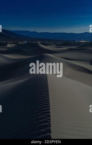 Vista notturna delle dune di sabbia di Mesquite Flat nel Death Valley National Park, California. Le dune di sabbia liscia si estendono sotto un cielo limpido e pieno di stelle, cre Foto Stock