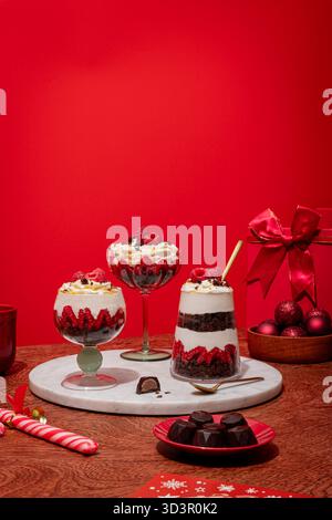 Dessert natalizio con strati di brownie ricchi, cremosi e lamponi freschi in un trifle. Delicatamente guarnita con cioccolato e. Foto Stock