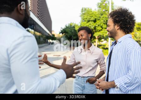 Team aziendale diversificato impegnato in vivaci discussioni all'aperto in un ambiente urbano, riflettendo il lavoro di squadra e la collaborazione in un ambiente urbano, con mod Foto Stock