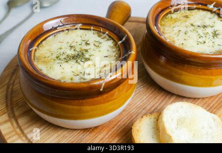 Il processo di cottura della zuppa di cipolle francesi. Due ciotole in ceramica con zuppa e formaggio fuso e diversi pezzi di baguette. Concetto di cucina tradizionale. H Foto Stock