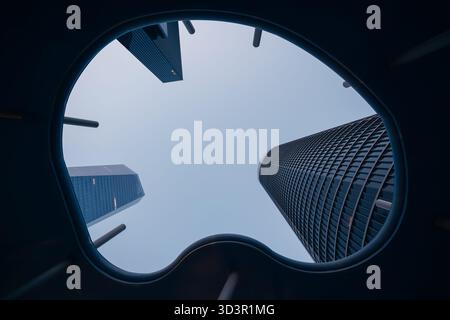 Un'impressionante ripresa dal basso del Cinco Torres di Madrid, che mostra l'architettura moderna e i grattacieli torreggianti contro un cielo blu limpido Foto Stock