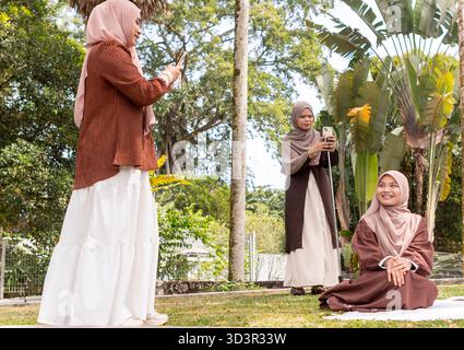 Tre giovani donne musulmane in hijab catturano insieme momenti di gioia all'aperto. Circondati dalla natura, abbracciano amicizia e stili di vita, mostrando G Foto Stock