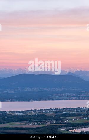 Vista panoramica di un affascinante tramonto sul Lago di Ginevra, con vivaci sfumature nel cielo che si riflettono sull'acqua tranquilla. Il momento perfetto in sé Foto Stock