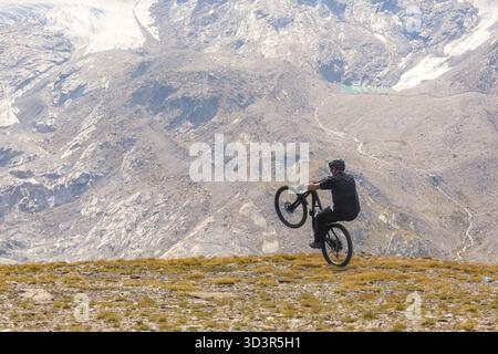Un mountain bike cavalca sapientemente lungo un aspro sentiero circondato dai paesaggi mozzafiato di Zermatt, Svizzera, catturando lo spirito di adve Foto Stock