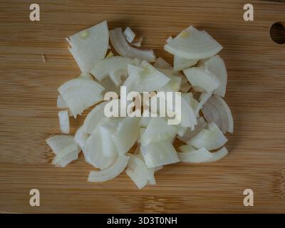 Vista dall'alto delle mani che tengono la cipolla appena tritata su un tagliere di legno per ricette o cibo contenuto blog per cucina e creatori di cucina. Alta qualità Foto Stock