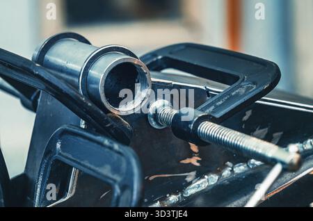 Il morsetto metallico tiene insieme le parti in ferro. Il morsetto è dotato di una vite filettata per il serraggio e la regolazione della pressione. Background industriale. Foto Stock