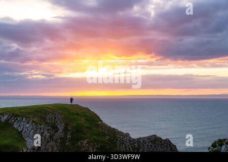 Fotografo che si gode il tramonto sulla Rhossili Bay, Swansea, Galles Foto Stock