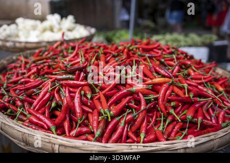 Chilis caldo rosso per la vendita immagazzinato in un grande arco tondo di vimini su un mercato di strada in Cina Foto Stock