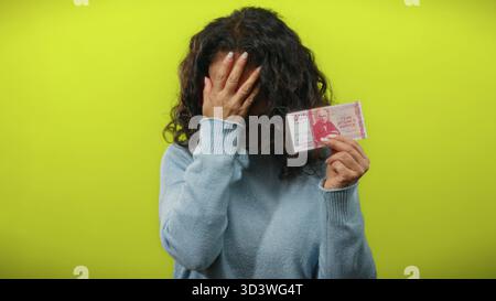La donna che tiene in mano la corona islandese sembra preoccupata da uno sfondo giallo brillante. Foto Stock