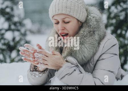La bella donna scalda le mani ghiacciate in inverno Foto Stock