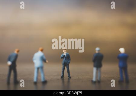 Uomo d'affari in miniatura in piedi su sfondo di legno Foto Stock