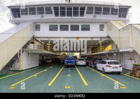 ROGAC, CROAZIA, 10.22.2025: La linea delle auto è un ponte per traghetti in un viaggio con veicoli affollati. Il pavimento verde, le marcature gialle e le auto parcheggiate creano un cro Foto Stock
