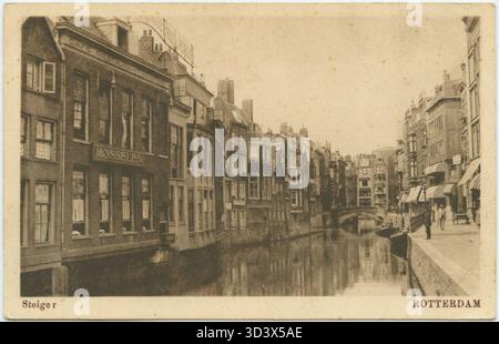 Questa cartolina del 1930 mostra la zona di Steiger a Rotterdam, con edifici da 9 a 12 sulla destra, il Weezenbrug sullo sfondo e la cupola di Sint-Dominicuskerk. L'immagine offre una vista delle infrastrutture e dell'architettura residenziale della città. Foto Stock