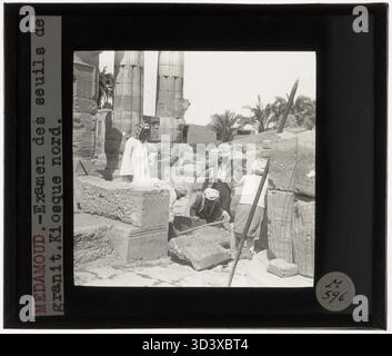 Fernand Bisson de la Roque e i lavoratori sono visti analizzare la soglia di granito del chiosco settentrionale al Tempio di Montu a Medamud. L'immagine è una diapositiva di vetro del 1925-1932. Foto Stock