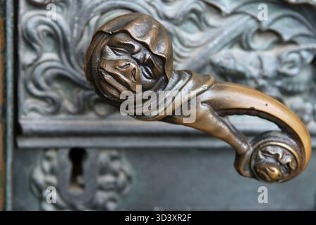 Maniglia per porta con faccia grimorata e serratura su un portale laterale della cattedrale di Colonia, NRW, Germania Foto Stock