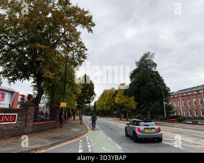 Manchester, Regno Unito - 30 settembre 2025: Strada autunnale di Manchester con ciclisti, automobili e marciapiedi alberati. Foto Stock