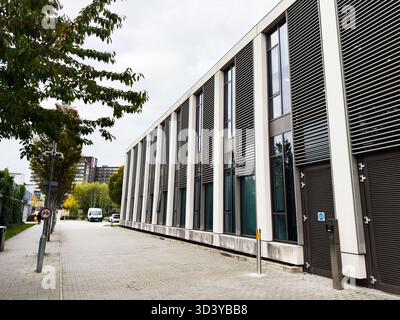 Manchester, Regno Unito - 30 settembre 2025: Un moderno edificio commerciale in una tranquilla via di Manchester con alte finestre e vegetazione. Foto Stock