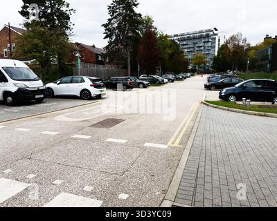 Manchester, Regno Unito - 30 settembre 2025: Tranquilla strada urbana di Manchester con auto parcheggiate, pedoni e uffici contemporanei accanto agli alberi. Foto Stock