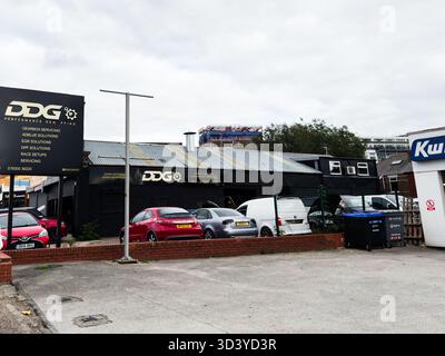 Manchester, Regno Unito - 30 settembre 2025: Auto parcheggiate fuori da un'officina di automobili di Manchester con segnaletica DDG e aree di servizio Foto Stock