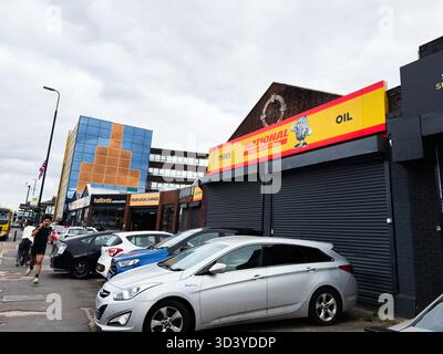 Manchester, Regno Unito - 30 settembre 2025: Trafficata Manchester Street con negozi, facciata colorata e auto parcheggiate lungo il marciapiede. Foto Stock