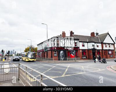 Manchester, Regno Unito - 30 settembre 2025: Vivace scena di Manchester Street con esterno pub, autobus, pedoni e architettura in mattoni. Foto Stock