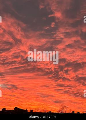 Un cielo mozzafiato al tramonto mostra nuvole vibranti in sfumature di arancio e rosa, creando un'atmosfera suggestiva con texture ricche e un'accattivante V Foto Stock