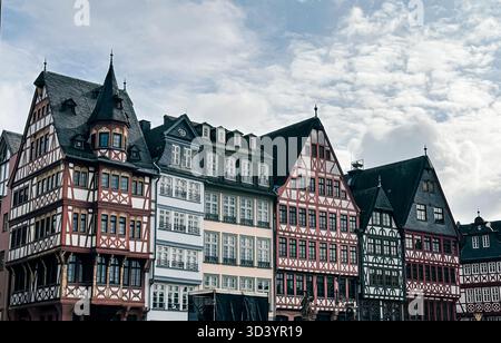 L'architettura storica mette in mostra una fila di case colorate per metà in legno con disegni intricati, poste contro un suggestivo cielo nuvoloso, che mette in risalto il cha Foto Stock