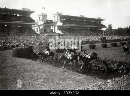 Una vista dell'autodromo di Auteuil a Bois de Boulogne, Parigi, con cavalli che saltano sopra gli ostacoli mentre migliaia di spettatori guardano dalle tribune. Foto Stock
